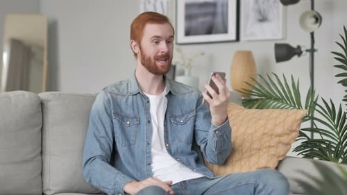 Smiling Man Video Calling on Smartphone at Home