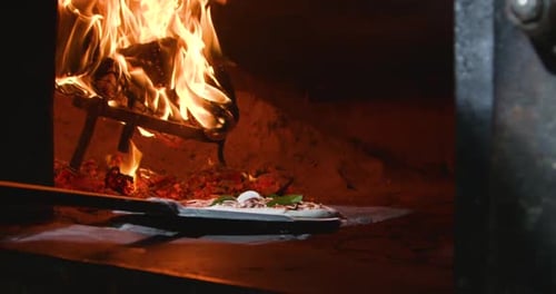 Chef putting pizza into oven
