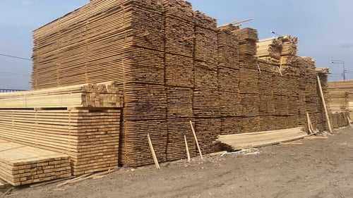 Stacked Lumber Awaiting Construction on a Dirt Lot