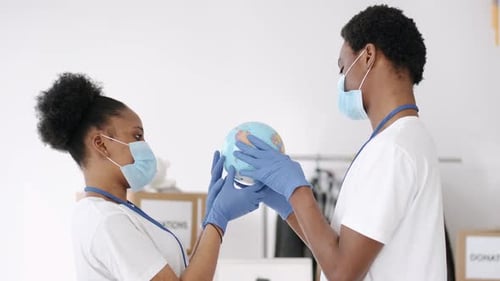 People Wearing Masks Holding Globe at Donations