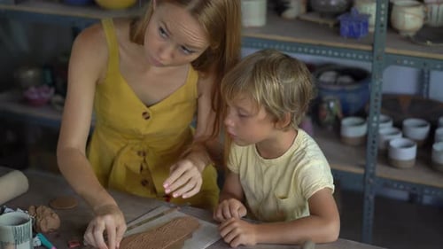 Woman and Child Making Pottery Together at Table