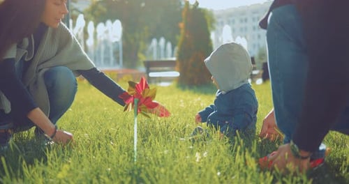 Parents and the Kid Play Together in the Meadow in the Park on a Sunny Day