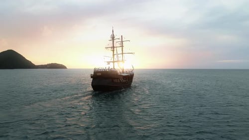 Filmmusik Rückansicht eines historischen Schiffes, das dem malerischen rosa-goldenen Sonnenuntergang entgegensegelt