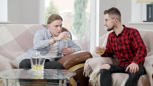 Deux amis de sexe masculin qui tintent, boivent du scotch et parlent