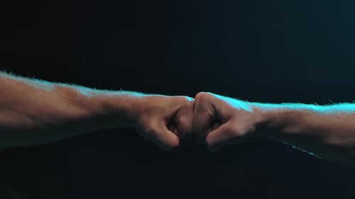 Forearms Connecting With a Fist Bump in the Dark