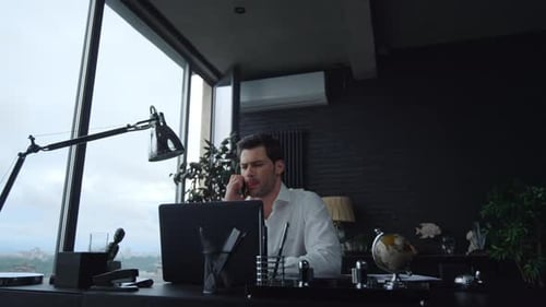 Professional Man Talking on Phone, Working on Laptop