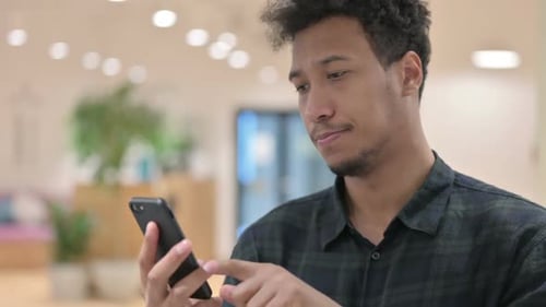 Young Adult Using Smartphone in Workplace Setting