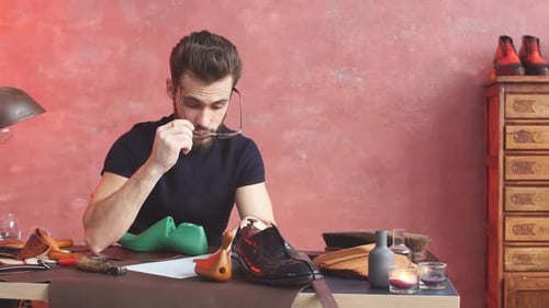 Shoemaker Designing Shoe at Desk