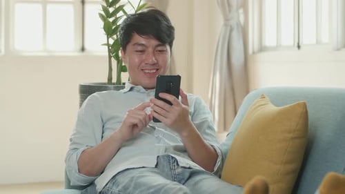 Young Man Relaxing at Home with Smartphone