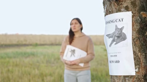 Nervous Lady with Flyers in Park Focus on Missing Cat Poster