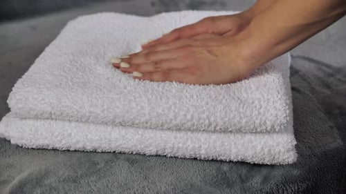 Close-up of Hands Putting Stack of Fresh White Bath Towels on the Bed Sheet. Room Service Maid