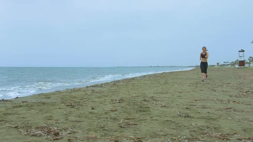 Young Woman With Fit Body Jogging on Sandy Beach in the Morning. Health Care
