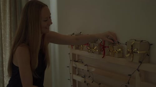 Woman Arranging Christmas Gifts on Shelf at Night