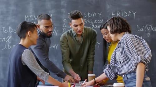 Young Adults Collaborating at an Office Chalkboard