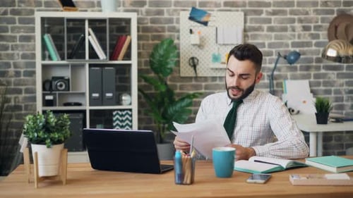 Unhappy Office Worker Reading Documents Sighing Thinking About Trouble at Work