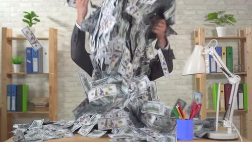 Expressive Businessman with a Pile of Dollars Sits on a Table in the Office of Slow Mo