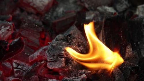 Fire flames over red hot aglow coals in grill
