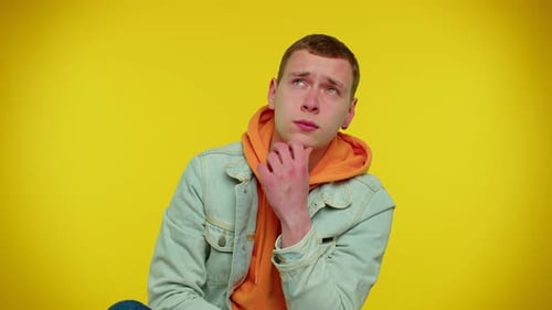 Pensive Young Adult Thinking Hard on Yellow Background