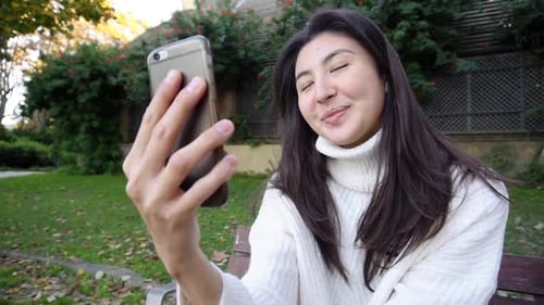 Smiling Woman Video Calling Outdoors on Smartphone