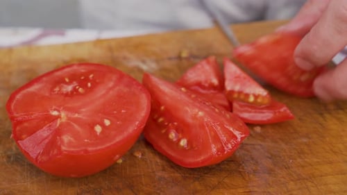Close View of Male Hands Cutting Fresh Red Tomato on Board to Prepare Salad