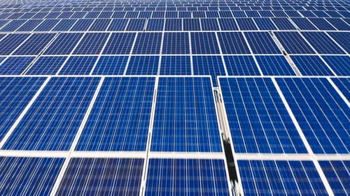 Luftaufnahmen über der Oberfläche von Sonnenkollektoren, die sich Reihe für Reihe vorwärts bewegen, über endlose blaue Zellen