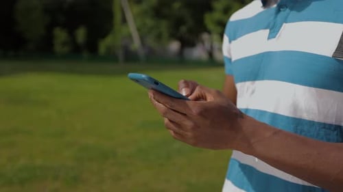 Close Up of Attractive Man with Backpack Typing Messages on His Smartphone