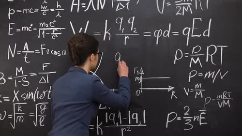 Woman Writing Equations on Blackboard Full of Formulas