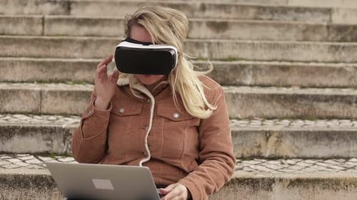 Woman Using VR Headset and Laptop on Steps