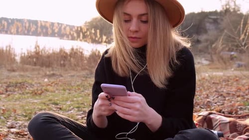 Woman Using Smartphone Relaxing by Lake Outdoors