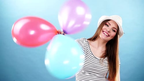 Young Woman Smiling with Balloons Against Blue Background