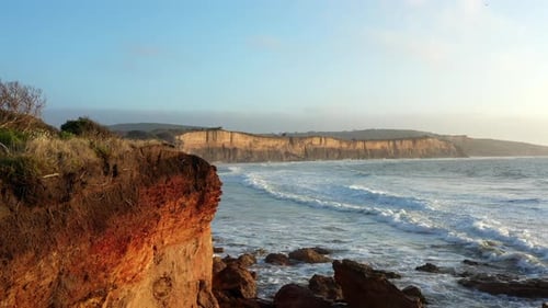 AERIAL Reveal Of Waves Rolling Into Eroded Cliffs During Golden Hour