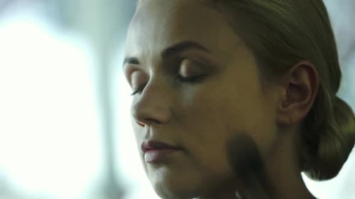 Makeup artist applying face powder on womens face