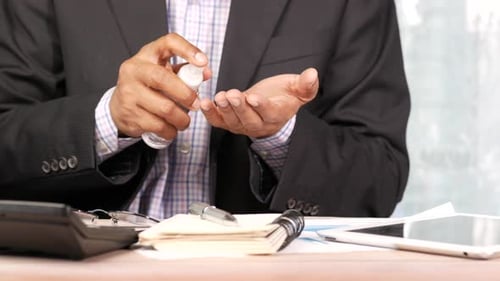Man Sprays Hand Sanitizer While at Desk