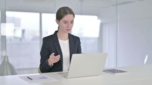 Woman in Suit on Video Call at Desk