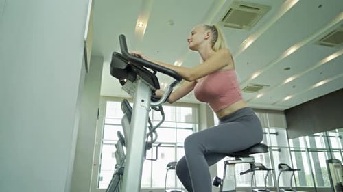 Woman Exercising on Stationary Bike at Gym
