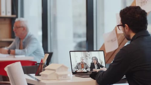 Male Architect Speaking with Two Coworkers via Video Call on Laptop