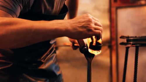 Glassblower reheating a piece of glass in furnace