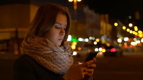 Woman Uses Smartphone at Night in City