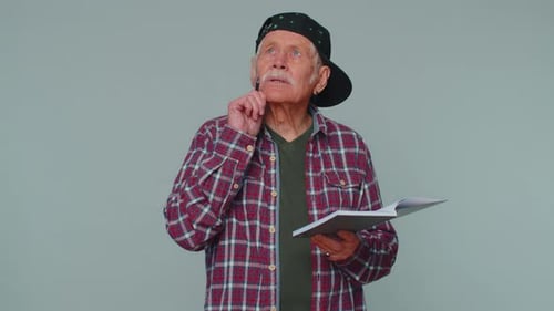 Senior Man Writes in Notebook and Thumbs Up