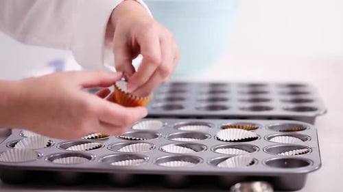 Time lapse. Lining cupcake pan with paper cupcake liners.