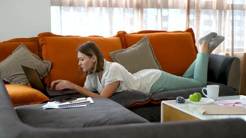 Young Woman Using Laptop Lying on Couch