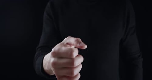 Man Makes a Fist on Black Background