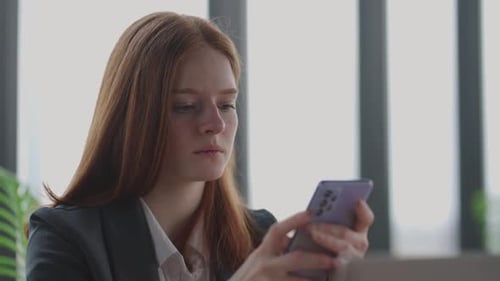 Young Businesswoman is Reading News in Mobile Phone Portrait of Serious and Depressed Lady in Office