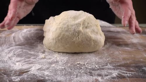 Hands Kneading Soft Dough on a Floured Board