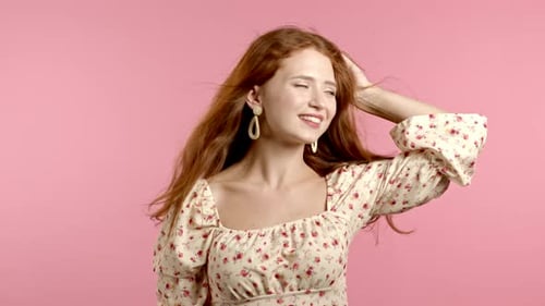 Young Woman in Floral Dress Looking To Camera, Flirting. Portrait of Beautiful Girl on Pink Wall