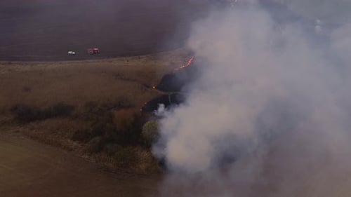 Field Fire Burns with Firetruck Nearby Aerial View