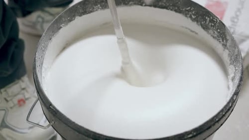 La masilla blanca para paredes se mezcla en un balde