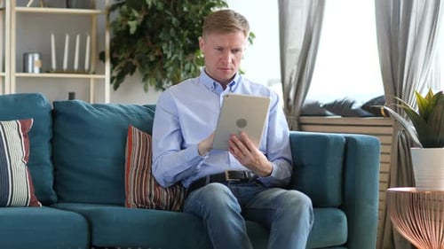 Adult Using Tablet in Living Room on Couch