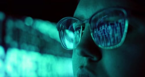 Nahaufnahme einer jungen erwachsenen Frau mit reflektierender Brille zur Analyse von Cybersicherheitscode-Daten