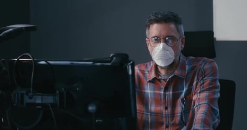 Man Working at Computer Wearing Surgical Mask